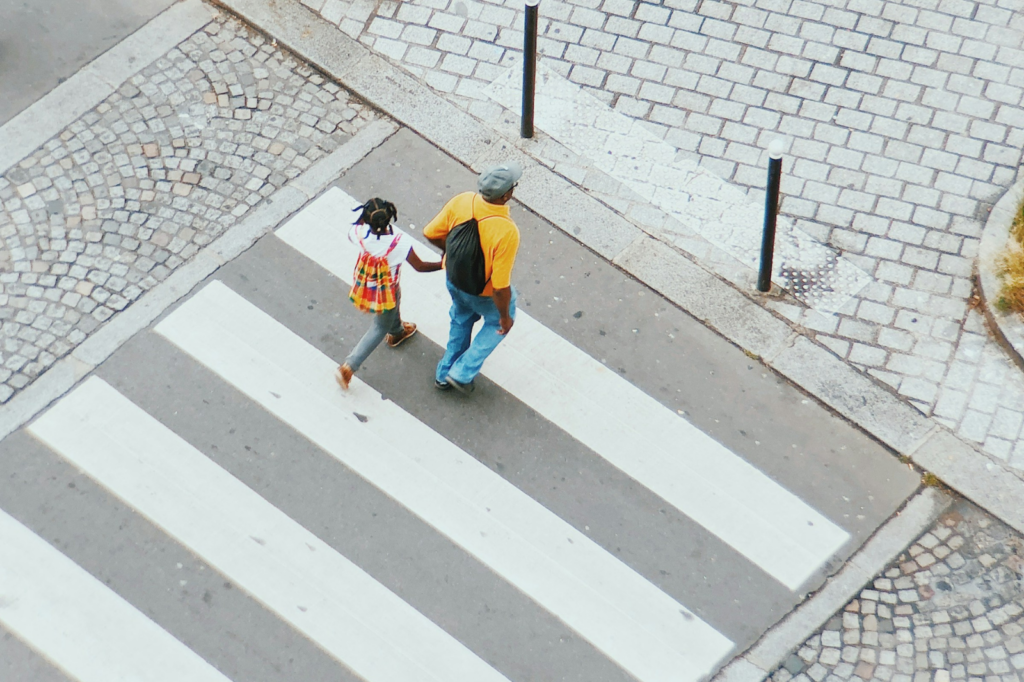 A man and his daughter cross the street